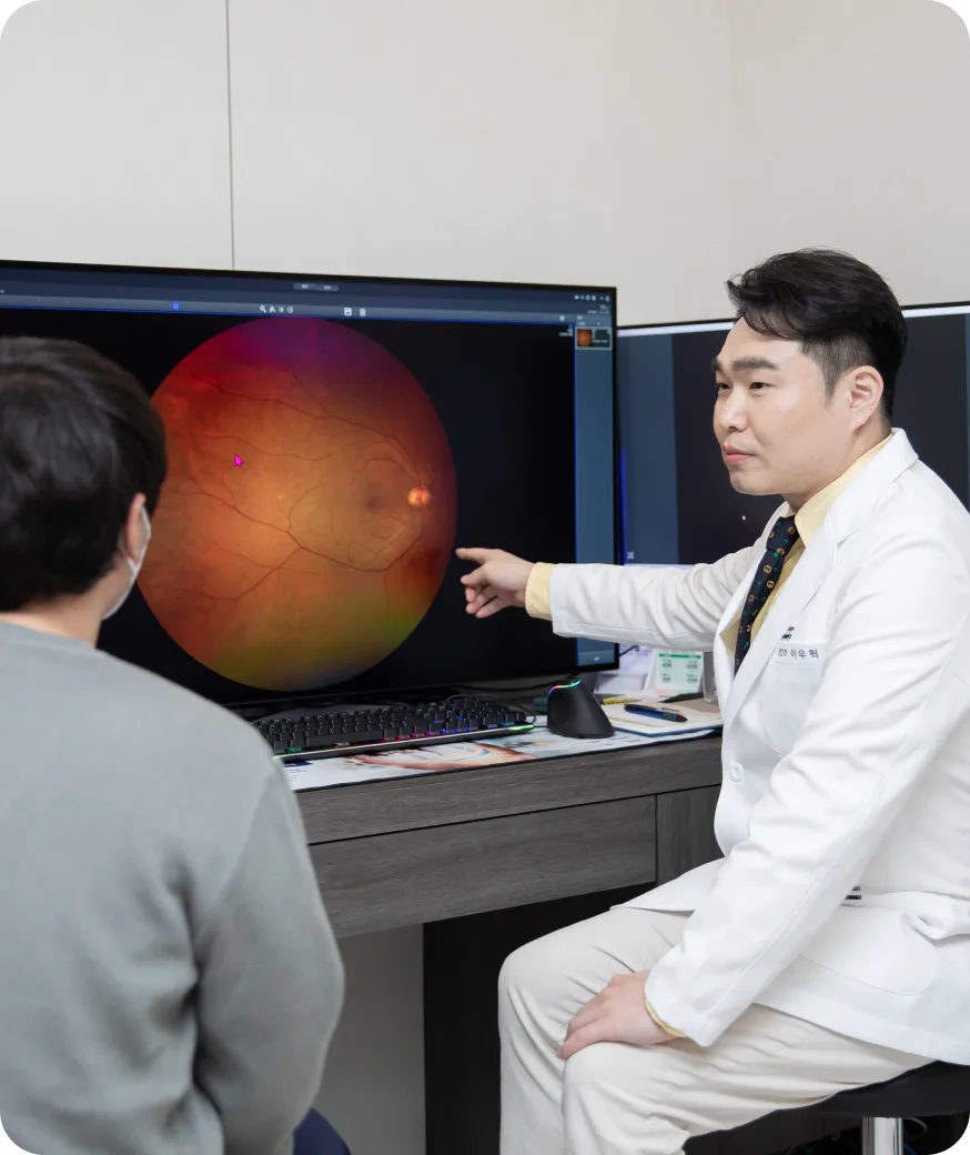 망막 촬영 영상을 가리키며 환자에게 설명하는 원장